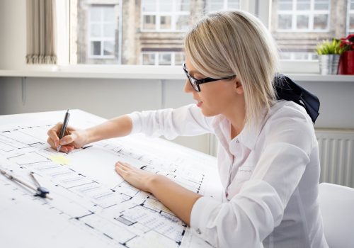 Young female architect working on blueprint