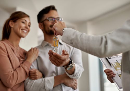 Close-up of a real estate agent giving to a couple keys of their new home.