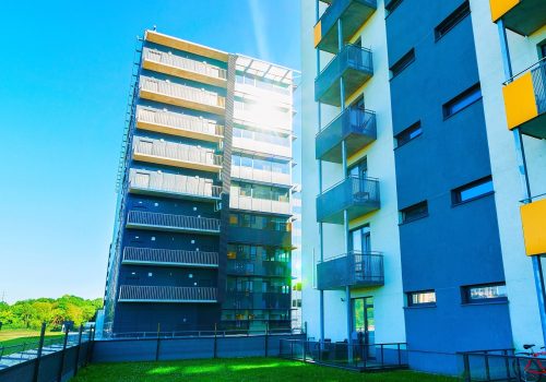 Apartment in residential building exterior. Housing structure at blue modern house of Europe. Rental home in city district on summer. Wall and glass high architecture for business property investment.